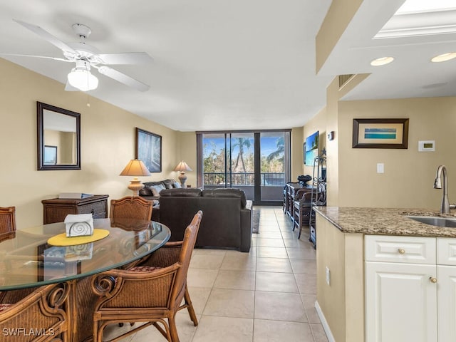 tiled dining area featuring ceiling fan, floor to ceiling windows, and sink