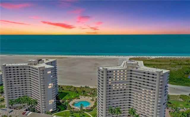 aerial view at dusk with a water view and a view of the beach