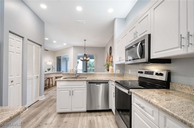 kitchen with sink, stainless steel appliances, a chandelier, decorative light fixtures, and white cabinets