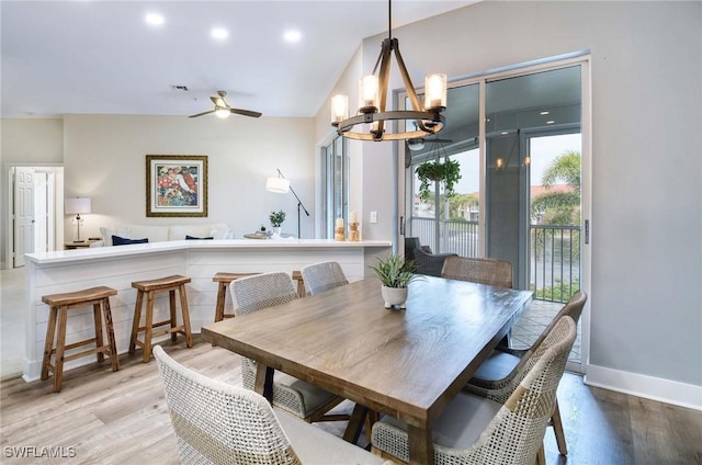 dining space with vaulted ceiling, light hardwood / wood-style floors, and ceiling fan with notable chandelier