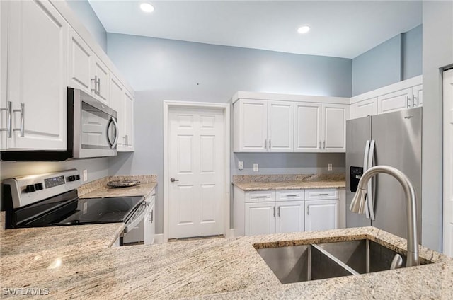 kitchen with light stone countertops, white cabinetry, sink, and stainless steel appliances