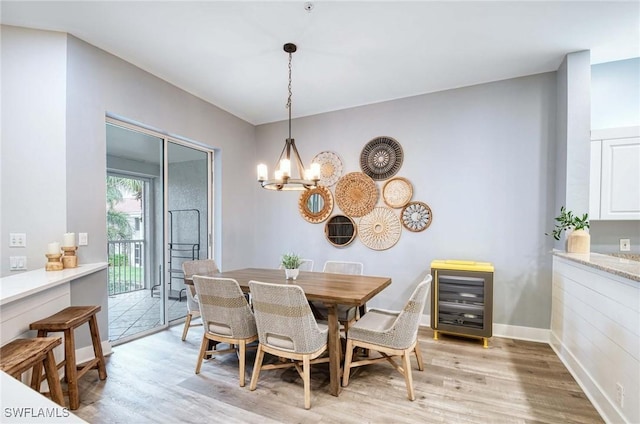 dining room featuring wine cooler, light hardwood / wood-style floors, and a notable chandelier