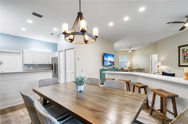 dining space featuring ceiling fan with notable chandelier and hardwood / wood-style flooring