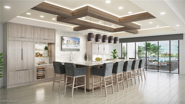 kitchen with coffered ceiling, hanging light fixtures, wine cooler, a large island, and a breakfast bar area