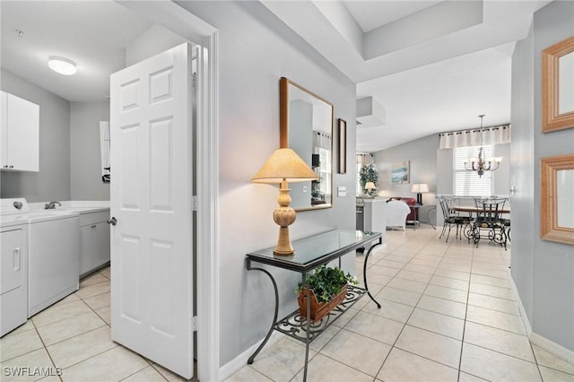 hallway with washer and dryer, light tile patterned flooring, and an inviting chandelier