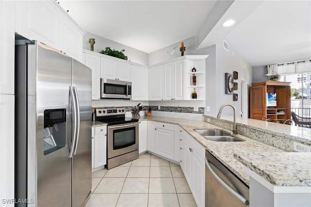 kitchen with kitchen peninsula, appliances with stainless steel finishes, light stone countertops, sink, and white cabinets