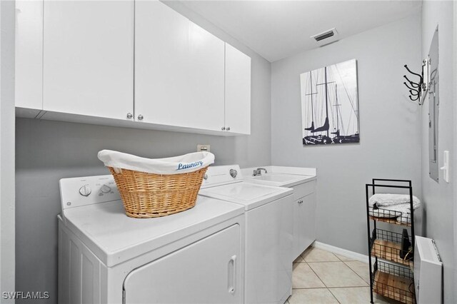 laundry area with cabinets, light tile patterned floors, washing machine and dryer, and sink