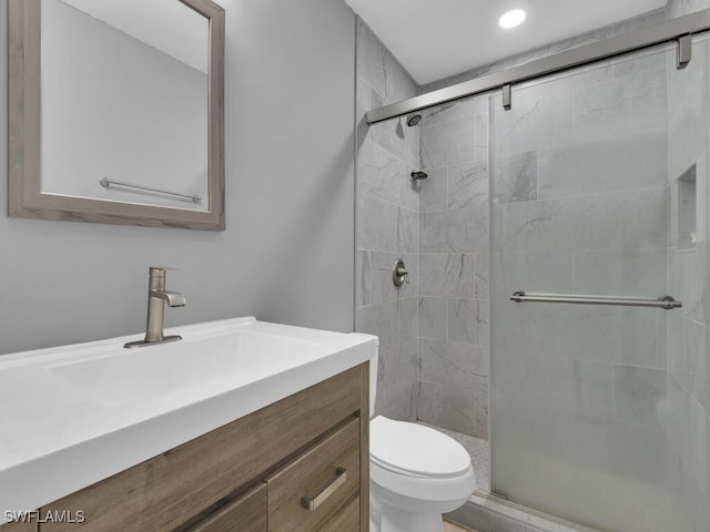 bathroom with vanity, a shower with shower door, and toilet