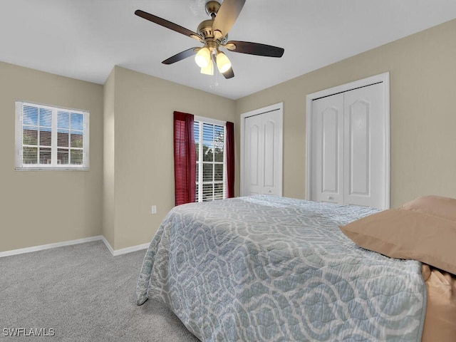 carpeted bedroom featuring ceiling fan and two closets