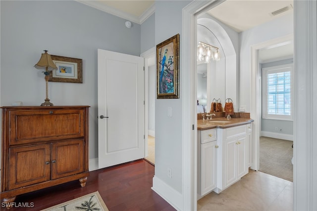 hallway featuring sink, crown molding, and light carpet