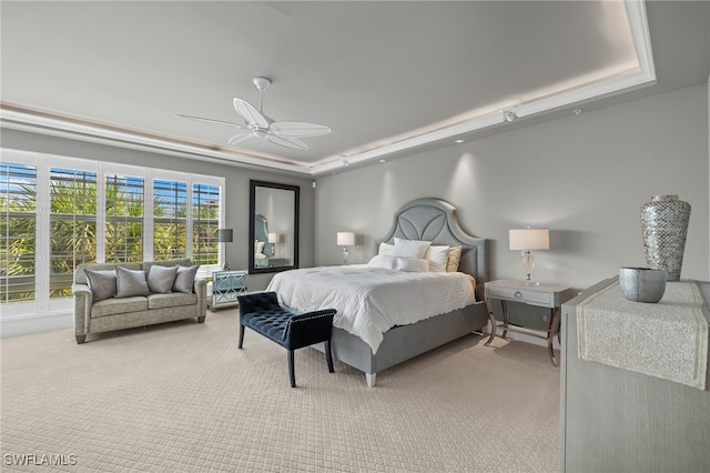 bedroom with ceiling fan, a raised ceiling, and light carpet