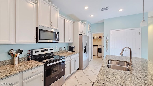 kitchen with light stone countertops, sink, stainless steel appliances, washing machine and dryer, and white cabinets