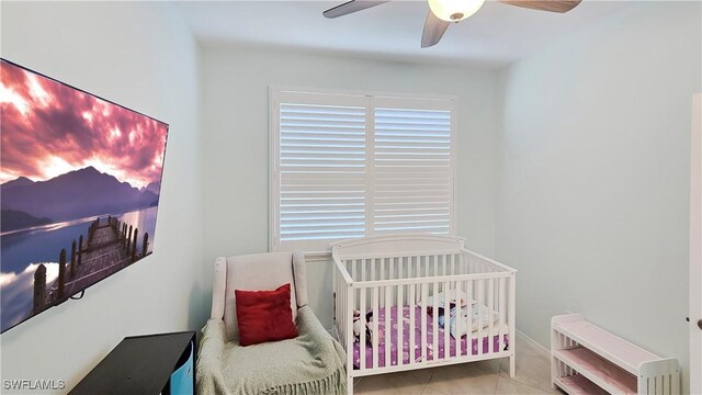 bedroom with a nursery area, ceiling fan, and light tile patterned flooring