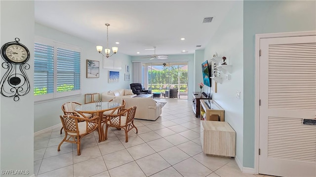 dining area featuring light tile patterned flooring and ceiling fan with notable chandelier