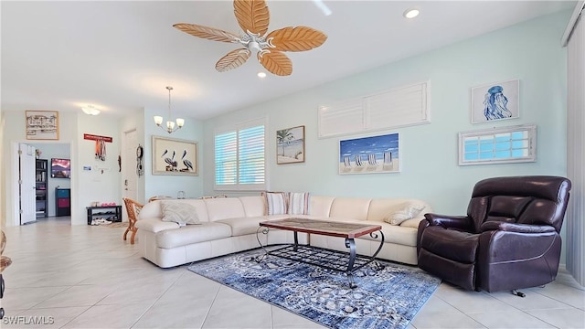 tiled living room with ceiling fan with notable chandelier