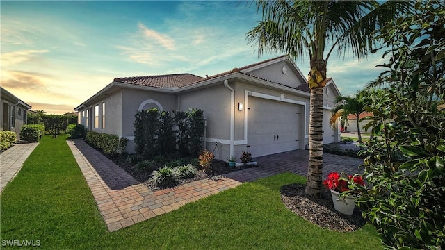 property exterior at dusk featuring a garage and a lawn