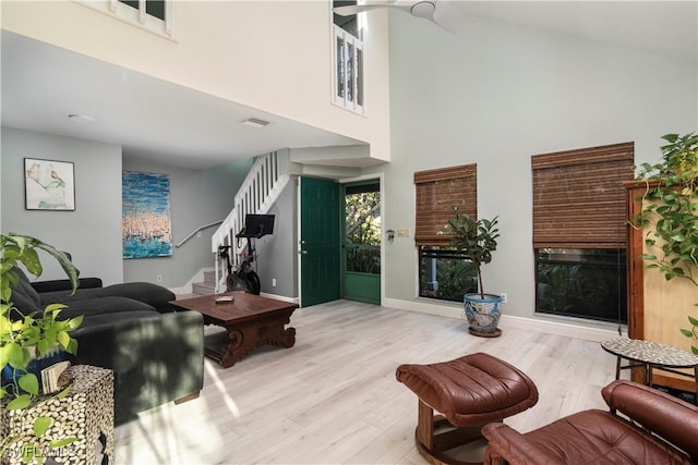 living room with a towering ceiling and light hardwood / wood-style flooring