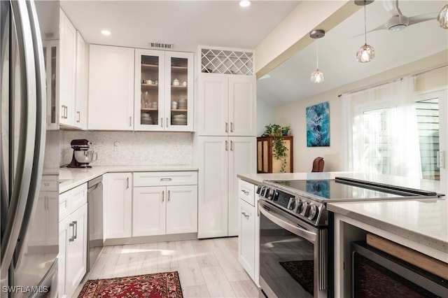 kitchen featuring white cabinets, appliances with stainless steel finishes, tasteful backsplash, and pendant lighting