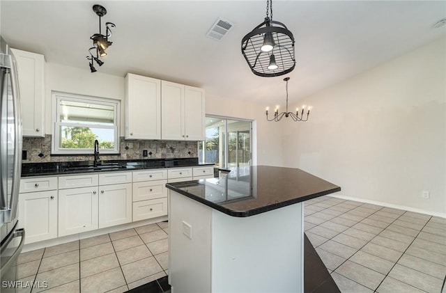 kitchen featuring pendant lighting, white cabinetry, a kitchen island, and sink