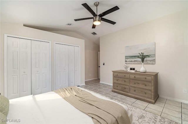 tiled bedroom with ceiling fan, two closets, and vaulted ceiling