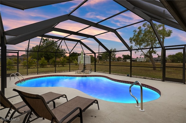 pool at dusk with a patio, a lanai, and a lawn