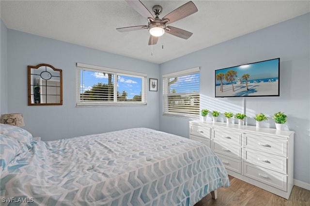 bedroom featuring a textured ceiling, ceiling fan, and light wood-type flooring