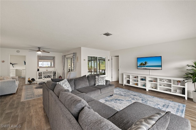 living room with dark wood-type flooring, plenty of natural light, and ceiling fan