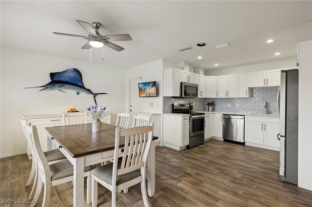 dining area with ceiling fan, dark hardwood / wood-style floors, sink, and a textured ceiling