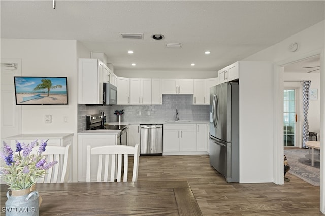 kitchen with dark wood-type flooring, sink, appliances with stainless steel finishes, decorative backsplash, and white cabinets