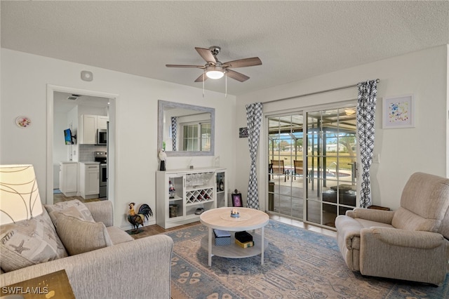 living room with ceiling fan and a textured ceiling