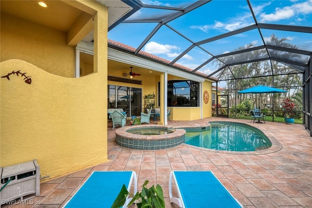 view of swimming pool with glass enclosure, a patio, a ceiling fan, and a pool with connected hot tub