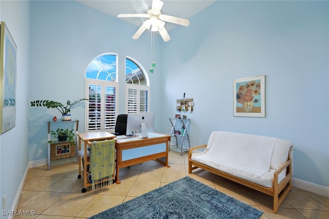 home office featuring light tile patterned floors, baseboards, a towering ceiling, and ceiling fan