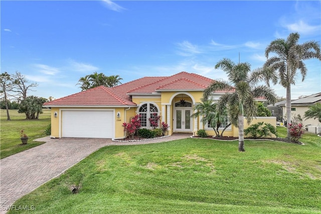 mediterranean / spanish home featuring a front lawn, a garage, and french doors