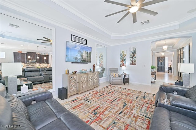 living room featuring a tray ceiling, ceiling fan, and ornamental molding