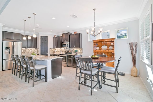 kitchen with appliances with stainless steel finishes, dark brown cabinetry, decorative light fixtures, and sink