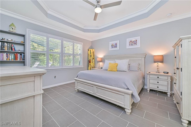 bedroom featuring dark tile patterned flooring, ceiling fan, ornamental molding, and a tray ceiling