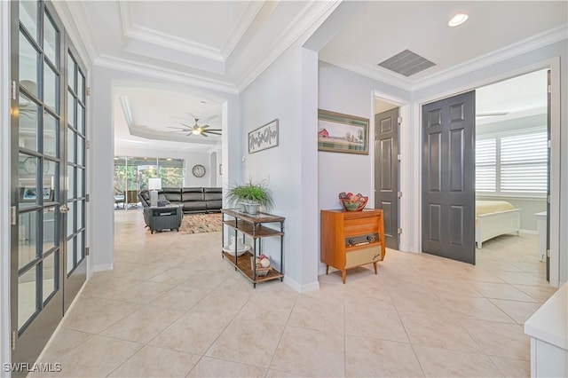 hallway featuring light tile patterned floors, a tray ceiling, and ornamental molding