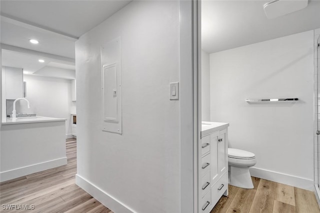 bathroom with toilet, vanity, baseboards, and wood finished floors