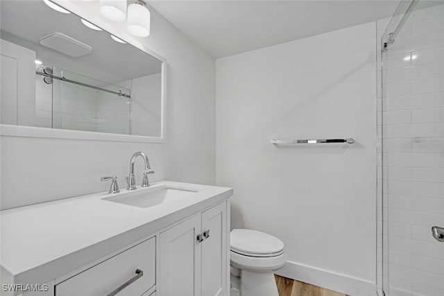 full bathroom featuring toilet, vanity, tiled shower, and wood finished floors