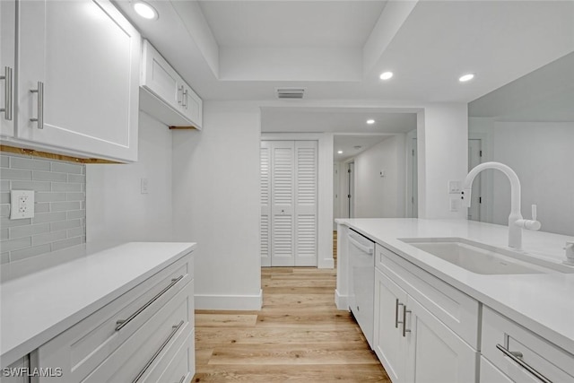 kitchen featuring a sink, visible vents, light countertops, dishwasher, and light wood finished floors