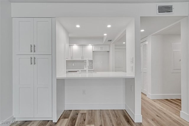 kitchen featuring baseboards, light wood-type flooring, visible vents, and white cabinetry