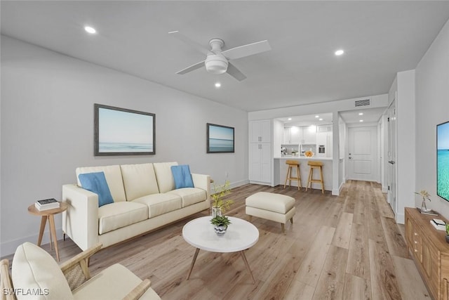 living room featuring visible vents, baseboards, light wood-style flooring, ceiling fan, and recessed lighting