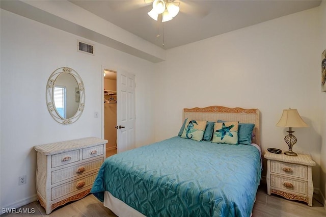 bedroom featuring hardwood / wood-style floors, ceiling fan, a spacious closet, and a closet