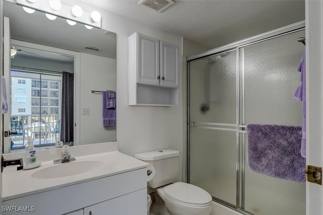 bathroom featuring a shower with door, vanity, and toilet