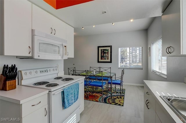 kitchen featuring light wood-type flooring, white appliances, white cabinetry, and sink