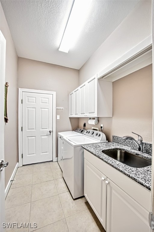 laundry area with cabinets, a textured ceiling, sink, light tile patterned floors, and washing machine and dryer