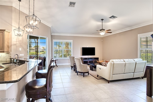 living room with sink, light tile patterned flooring, ceiling fan with notable chandelier, and ornamental molding