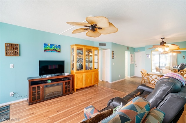 living room with ceiling fan, baseboards, visible vents, and light wood-style floors