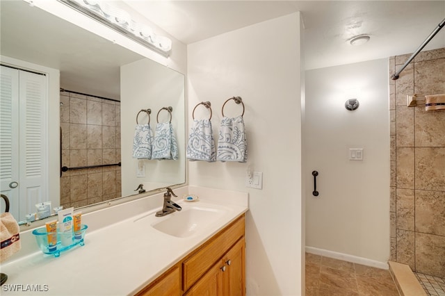 bathroom featuring a closet, a tile shower, vanity, and baseboards