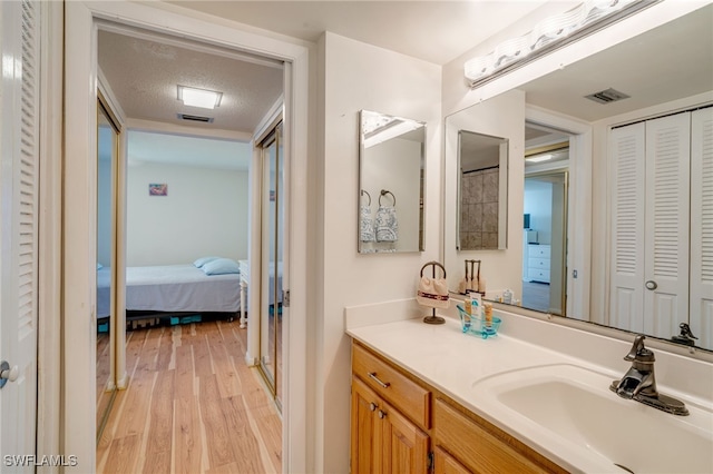 bathroom with visible vents, wood finished floors, a textured ceiling, vanity, and a closet